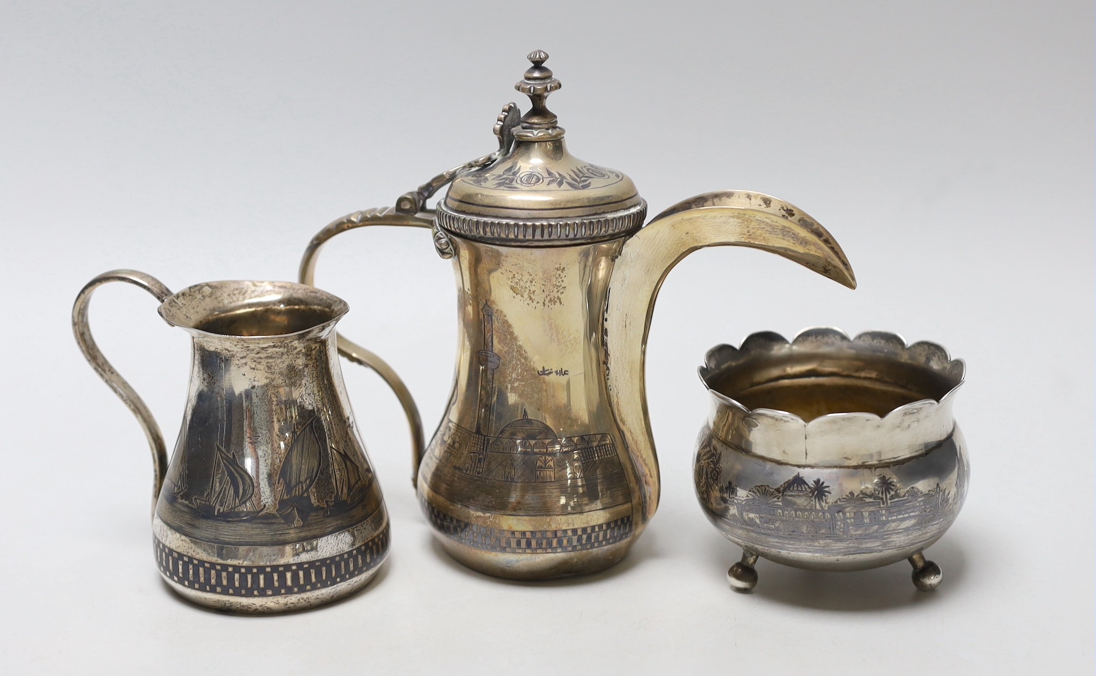 A Middle Eastern white metal and niello cream jug, a sugar bowl and coffee pot, 16.4cm, gross weight 22oz.